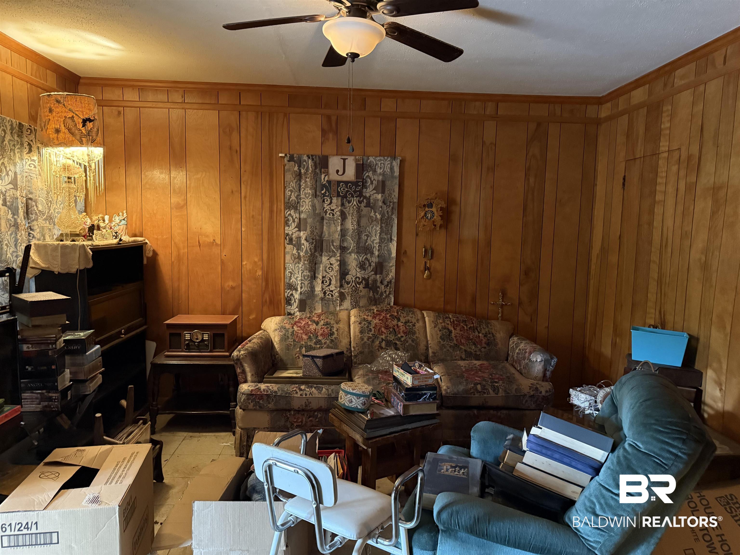 157 North Shelton Beach Road Eight Mile, AL 36613 - Photo 2 of 5 Living room featuring ceiling fan, wood walls, and ornamental molding