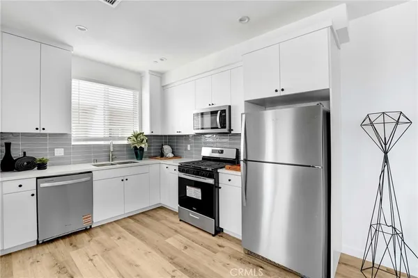a kitchen with a refrigerator a stove a sink and white cabinets