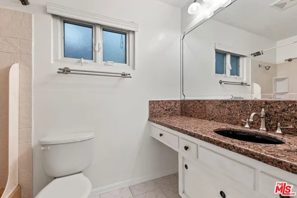 a bathroom with a granite countertop toilet sink and mirror