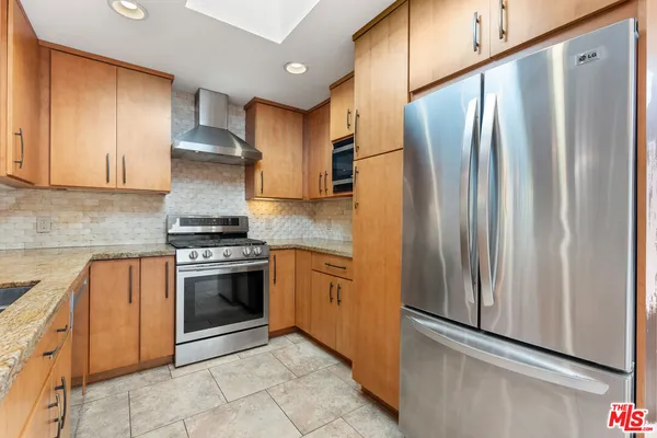 a kitchen with stainless steel appliances granite countertop a refrigerator sink and stove