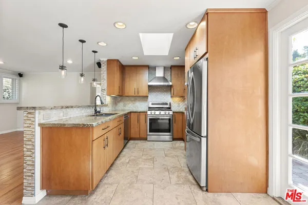 a large kitchen with stainless steel appliances kitchen island granite countertop a refrigerator and a sink
