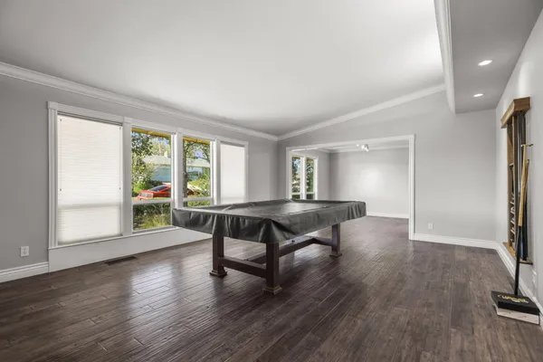 a view of a room with wooden floor pool table and windows