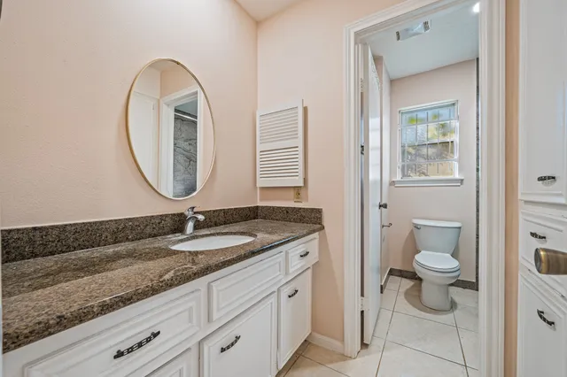 a bathroom with a granite countertop sink a toilet and a mirror