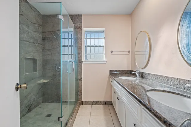 a spacious bathroom with a granite countertop sink a mirror and a shower