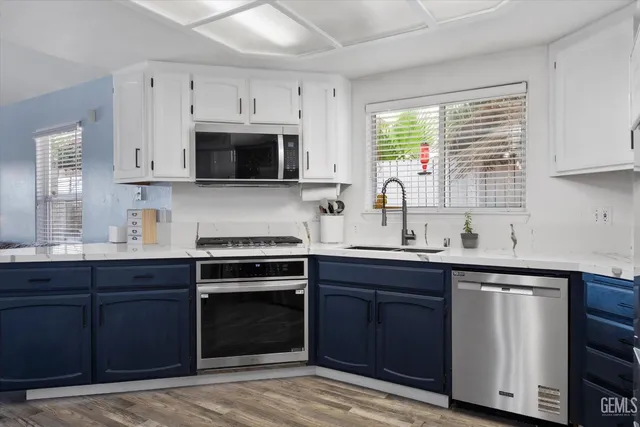 a kitchen with stainless steel appliances granite countertop a refrigerator stove a sink and dishwasher with wooden floor