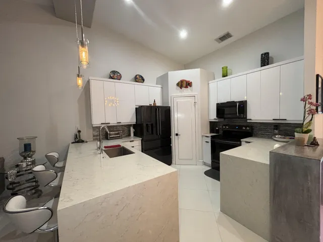 a kitchen with stainless steel appliances kitchen island granite countertop a refrigerator and a stove top oven with wooden floor