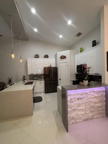 a kitchen with stainless steel appliances kitchen island granite countertop a refrigerator and a stove top oven