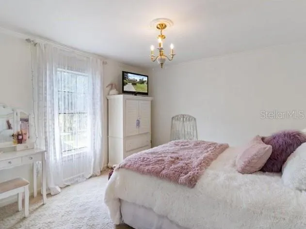 a bedroom with a bed chandelier and window