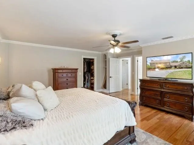 a bedroom with a large bed and a flat tv screen on dresser