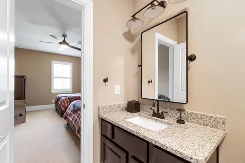 a en suite bathroom with a granite countertop sink and a mirror
