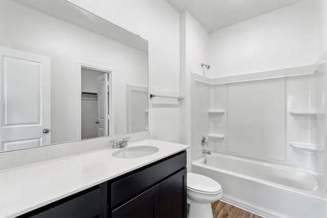 a bathroom with a bathtub shower sink vanity mirror and toilet