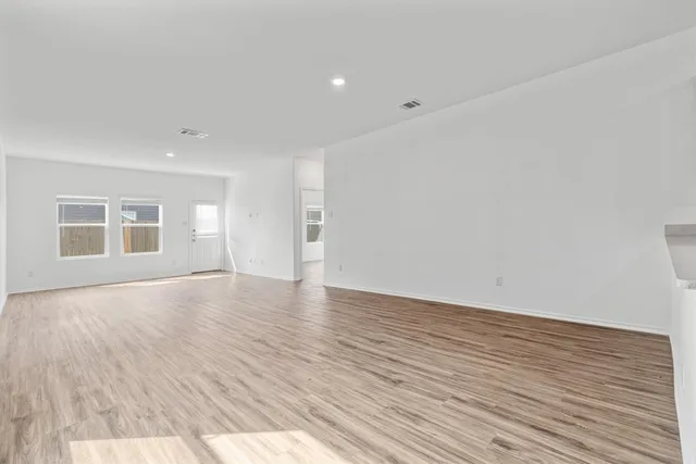 a view of empty room with wooden floor and windows