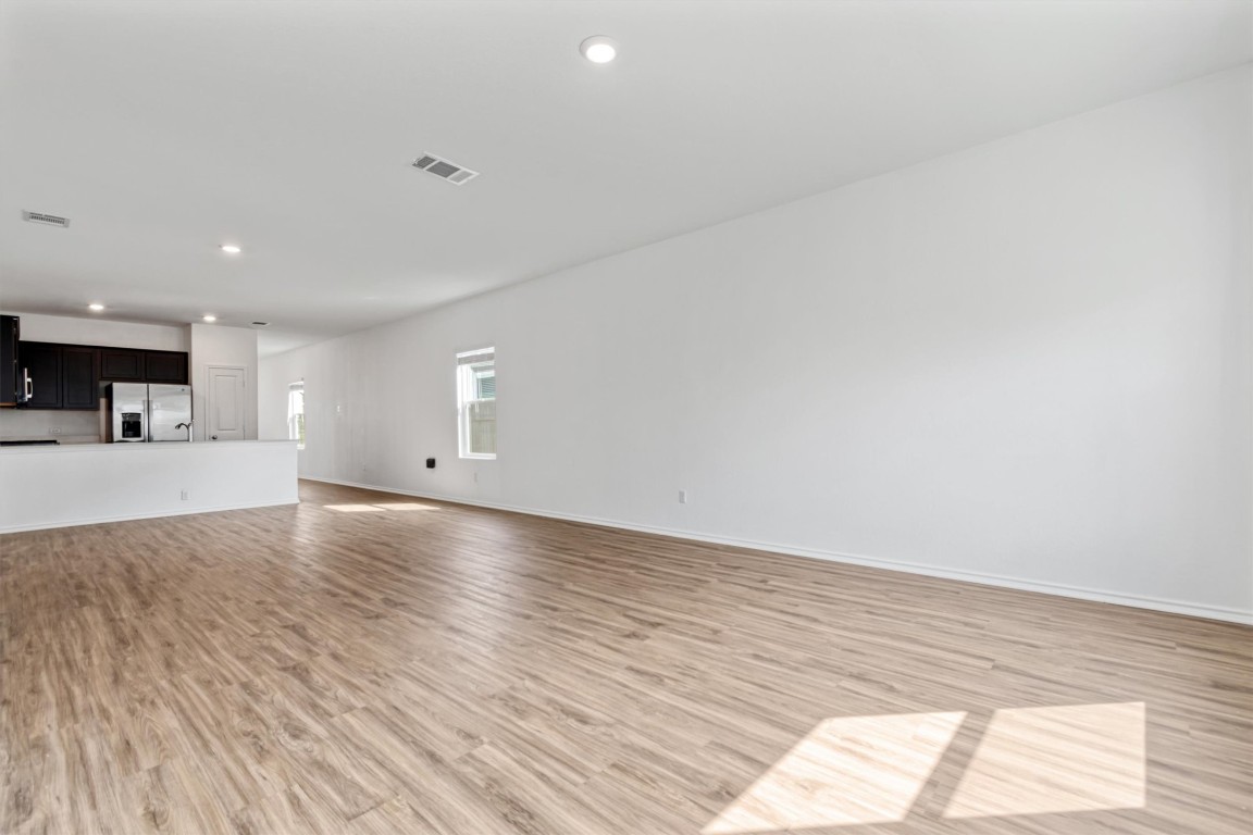 348 Soapstone Pass Maxwell, TX 78656 - Photo 7 of 18 a view of an empty room and kitchen with wooden floor