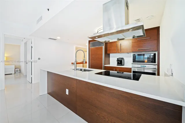 a large white kitchen with stainless steel appliances a sink and cabinets