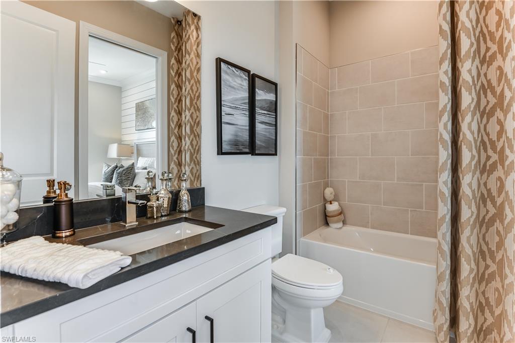 15336 Lucerna Street, Unit 203 Naples, FL 34114 - Photo 12 of 15 a bathroom with a granite countertop sink a toilet a mirror and bathtub