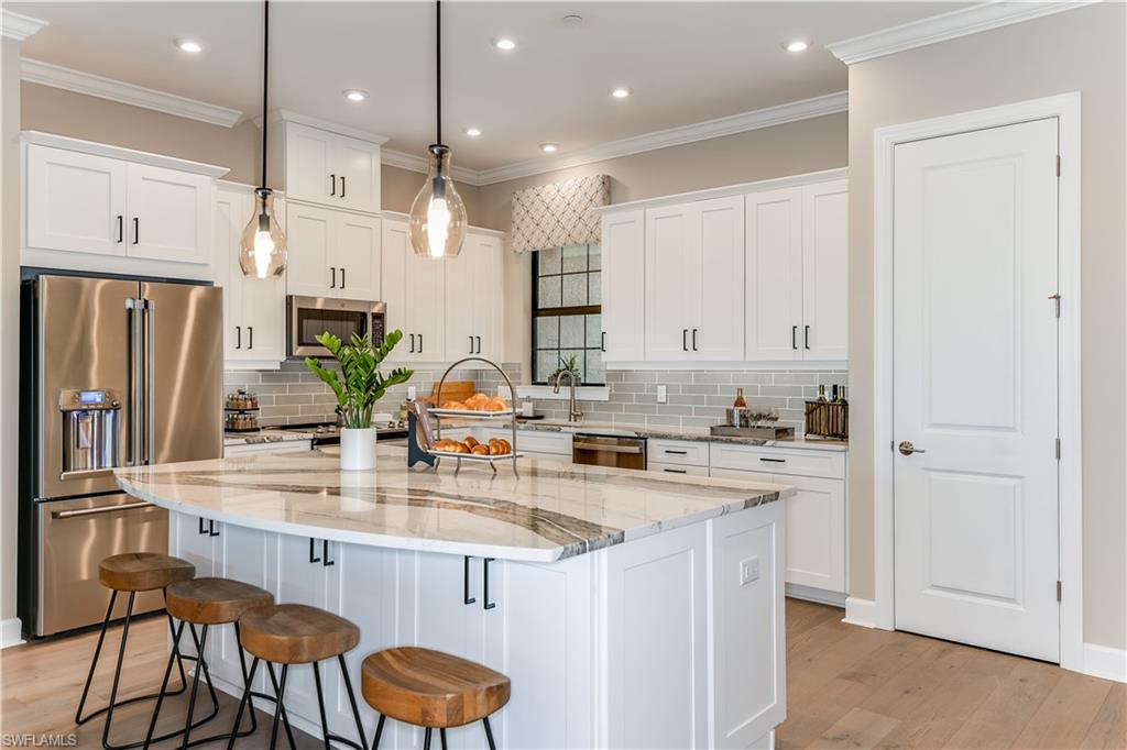15336 Lucerna Street, Unit 203 Naples, FL 34114 - Photo 5 of 15 a kitchen with stainless steel appliances granite countertop a sink a stove a refrigerator and island with wooden floor