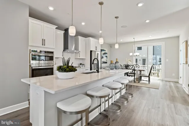 a kitchen with stainless steel appliances a dining table chairs stove and white cabinets