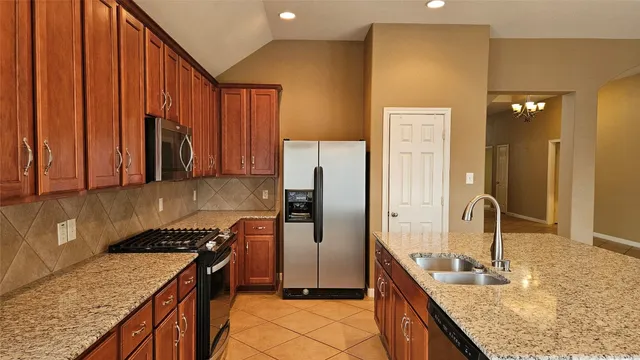 a kitchen with stainless steel appliances granite countertop a stove a refrigerator and a sink