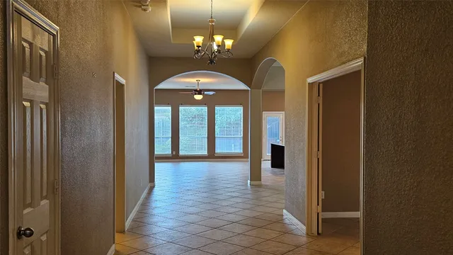 a hallway with wooden floor and chandelier