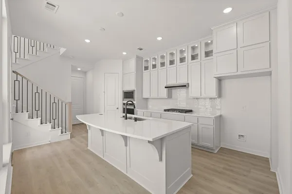 a large white kitchen with a white stove top oven and white cabinets