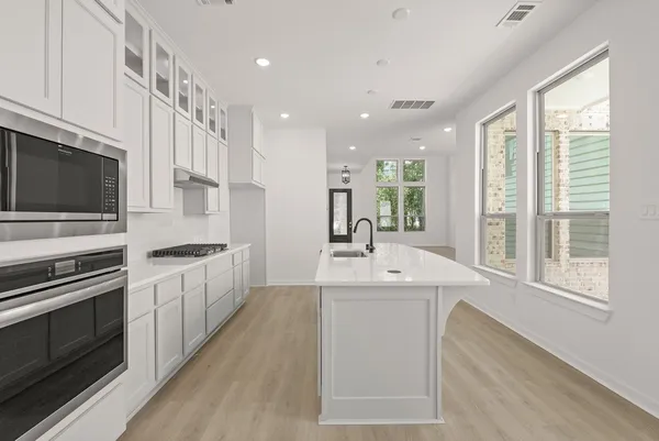 a large kitchen with stainless steel appliances a sink and cabinets