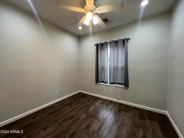 an empty room with wooden floor and fan