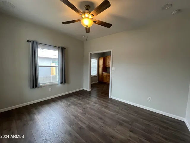 a view of an empty room with window and wooden floor