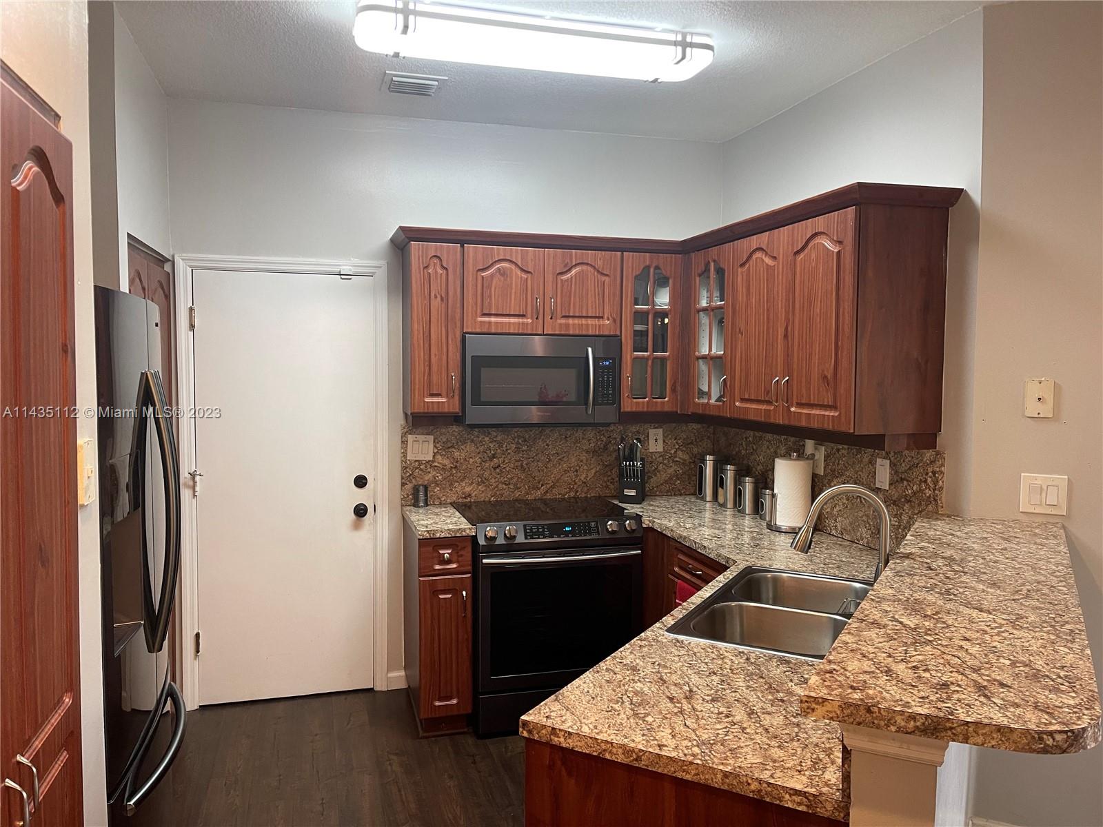 1990 Southwest 103rd Terrace Miramar, FL 33025 - Photo 8 of 19 a kitchen with granite countertop stainless steel appliances and wooden cabinets