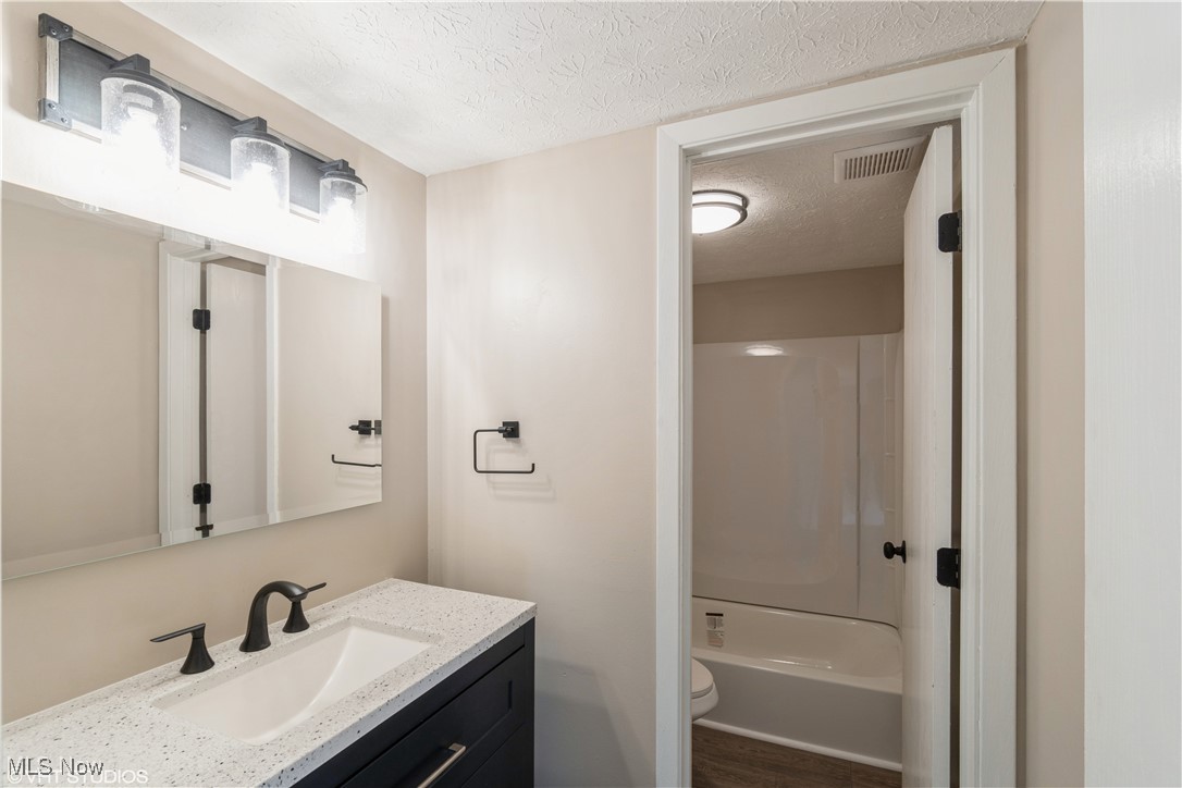 3725 Mayfield Road Cleveland Heights, OH 44121 - Photo 14 of 16 Full bathroom with tub / shower combination, vanity, a textured ceiling, hardwood / wood-style flooring, and toilet