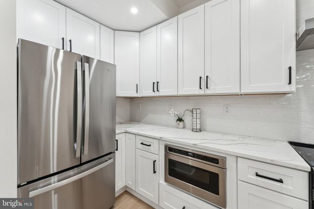 a kitchen with stainless steel appliances white cabinets and a refrigerator