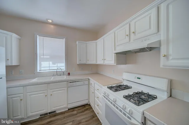 a kitchen with white cabinets stove and sink