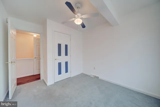 an empty room with closet and ceiling fan