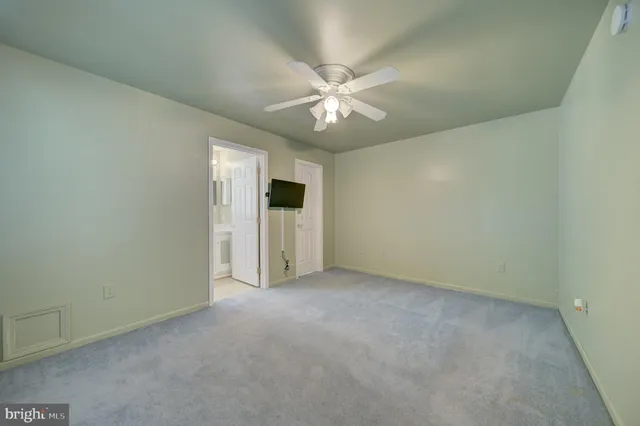 an empty room with chandelier fan and windows