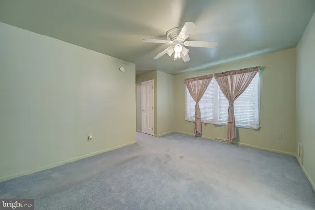 an empty room with a fan & a window