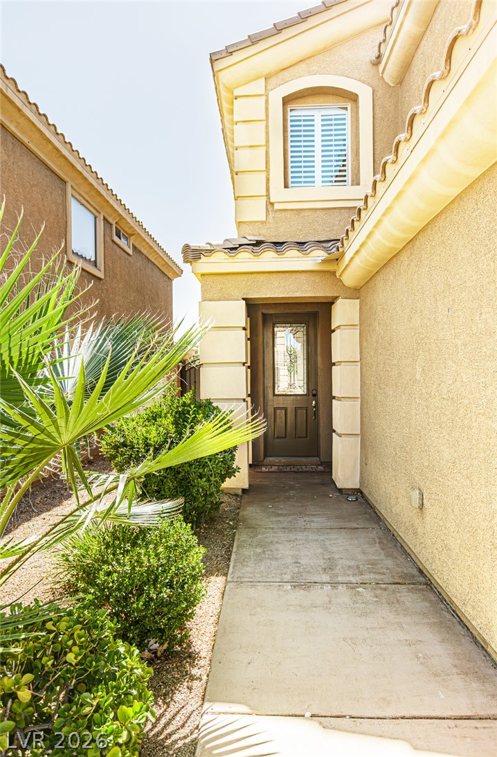 75 Tall Ruff Drive Las Vegas, NV 89148 - Photo 4 of 64 A concrete walkway leads to the private entrance of this multi-level stucco home.