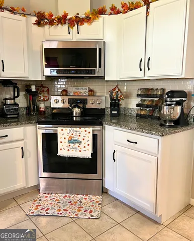 a kitchen with stainless steel appliances granite countertop a stove top oven a sink a counter space and cabinets