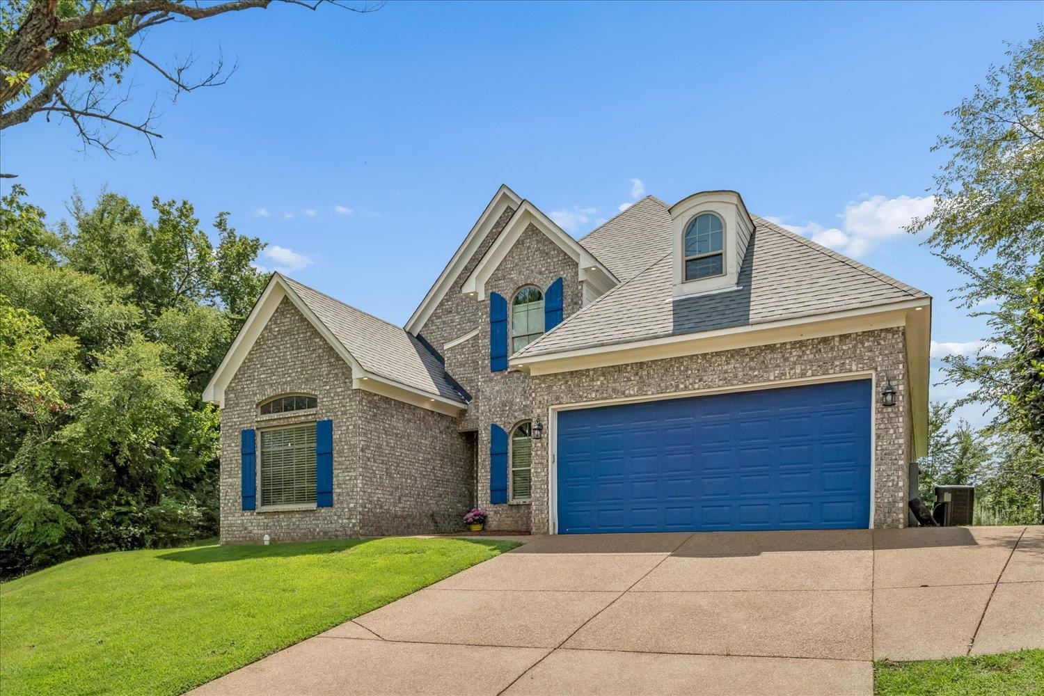 8867 Hampton Court Road East Memphis, TN 38016 - Photo 2 of 23 Brick and stone exterior with elegant architectural details, including a peaked roofline, arched dormer window, and blue shutters