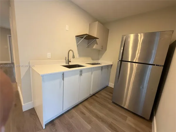 a kitchen with sink a refrigerator and wooden floor