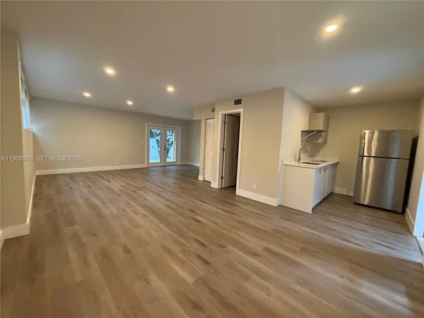 a view of a kitchen with refrigerator and wooden floor