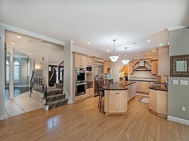 a kitchen with stainless steel appliances kitchen island wooden floors and white cabinets