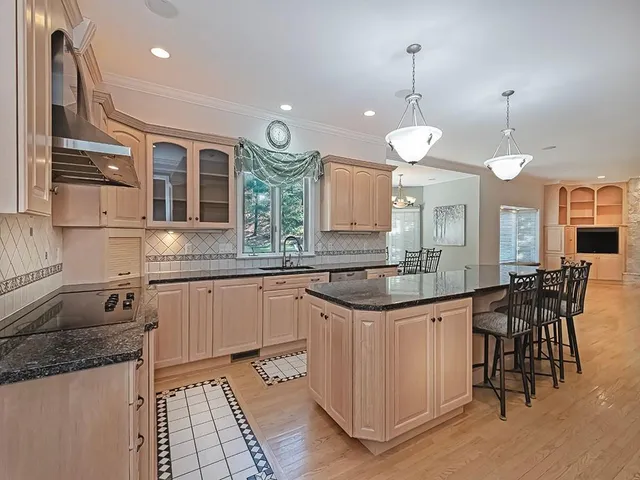 a kitchen with stainless steel appliances granite countertop a stove a sink a oven a dining table and chairs with wooden floor