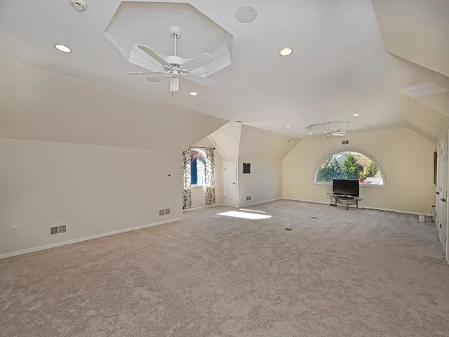 an empty room with potted plants and a chandelier fan