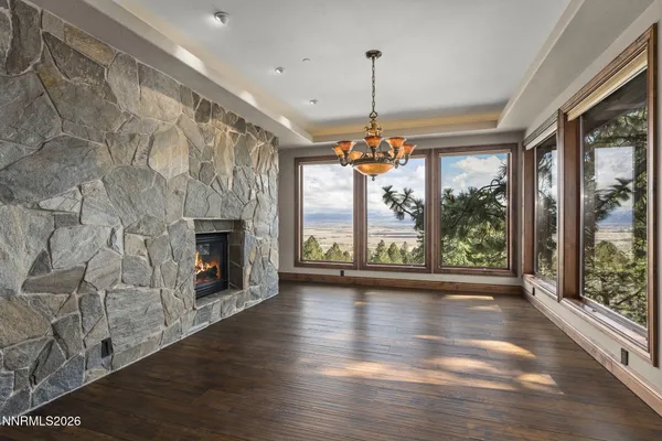 a view of an empty room with wooden floor and a fireplace