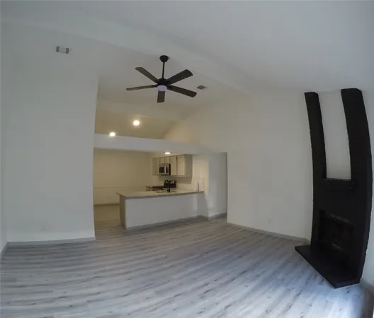 a view of a hallway to a room with wooden floor and a window