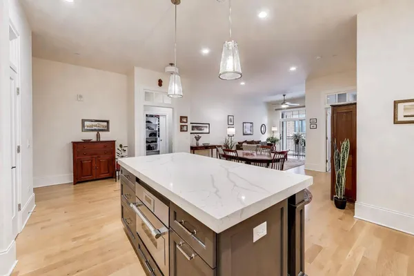 a kitchen with stainless steel appliances granite countertop a stove a sink a refrigerator a kitchen island with a dining table and chairs