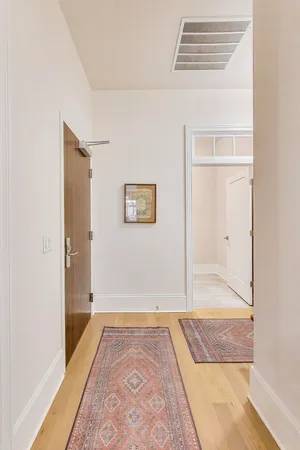 a view of a hallway to a house with wooden floor and a potted plant