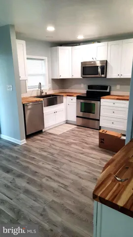 a large kitchen with wooden floors and stainless steel appliances