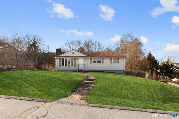 a view of a house with a big yard plants and large trees