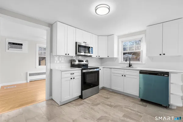 a kitchen with cabinets stainless steel appliances and a window