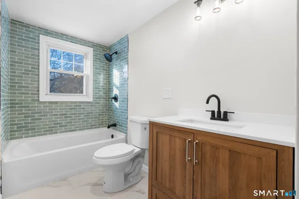 a bathroom with a toilet a sink a mirror and a bathtub